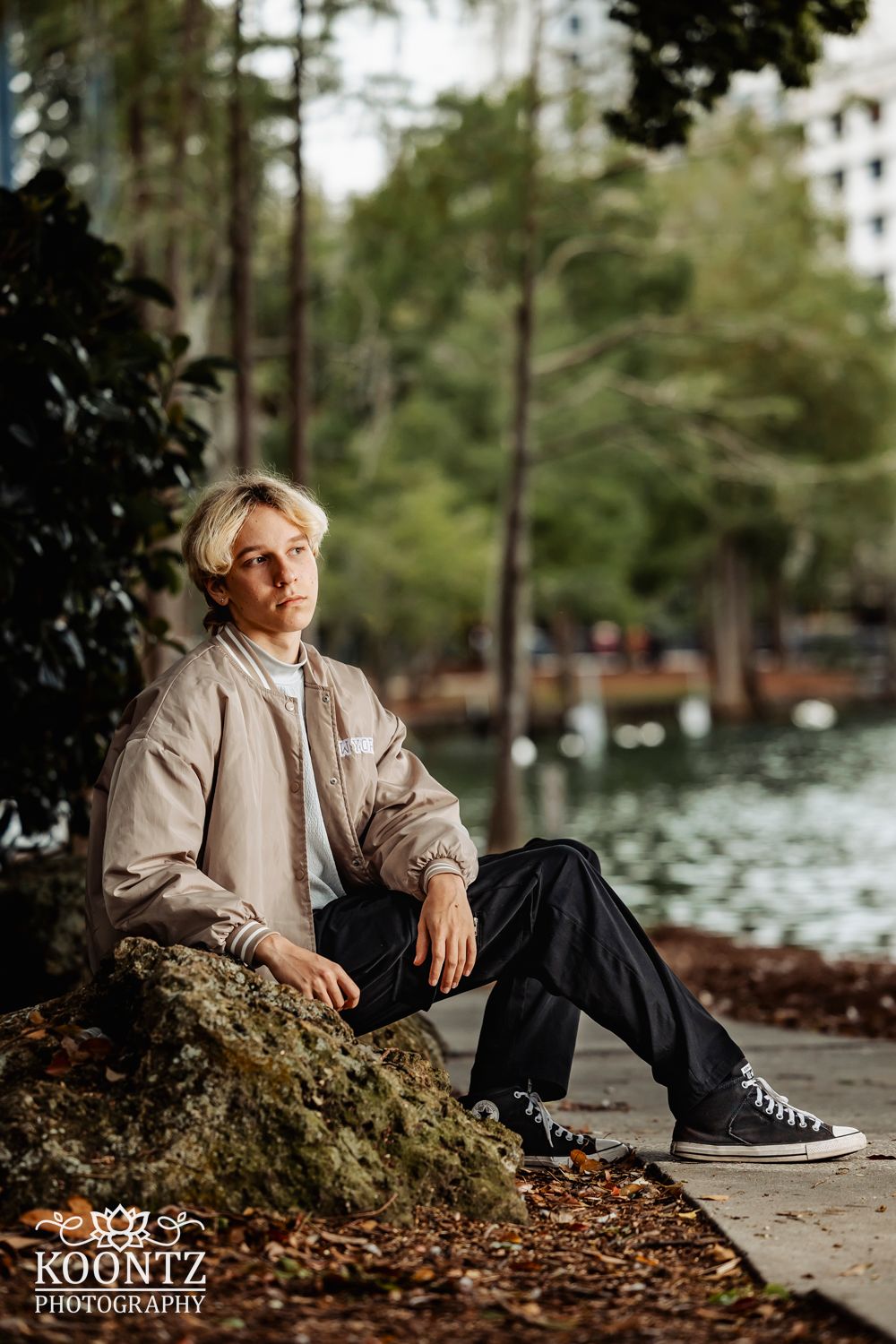 Portrait by a waterfront park with fall foliage in the background.
