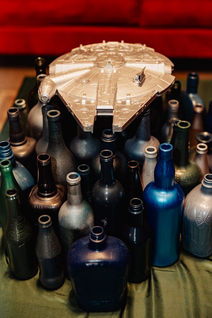 A model of the Millennium Falcon sits atop a collection of colorful glass bottles.