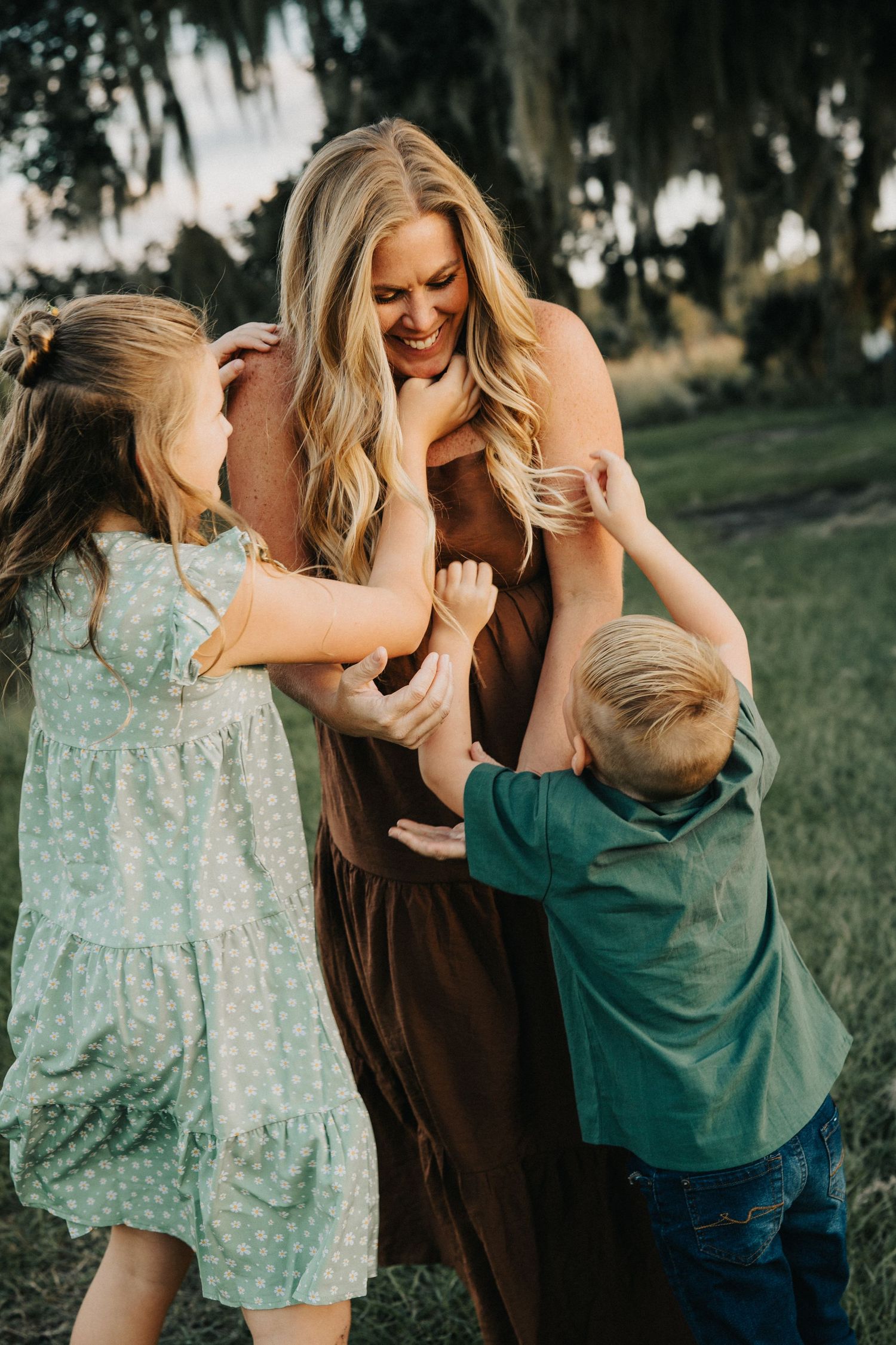 A joyful outdoor family moment with barefoot play and laughter in a brown dress and green shirt.