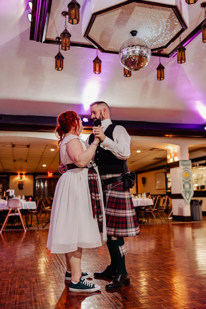Bride and groom sharing first dance under disco ball and lanterns at Scottish wedding reception.