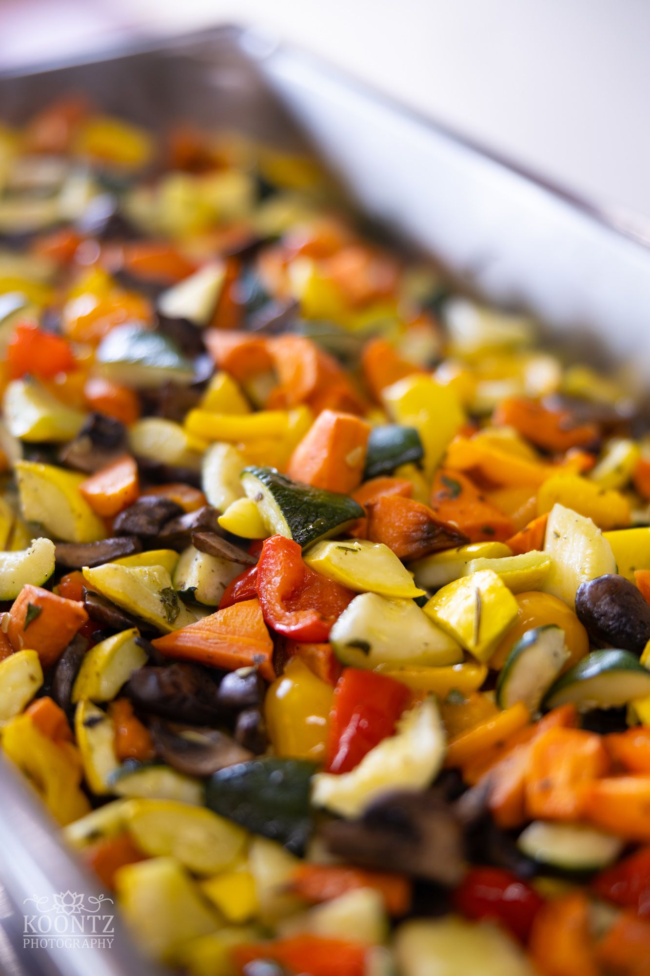 Colorful roasted vegetable medley with peppers, zucchini, and carrots in a baking dish.