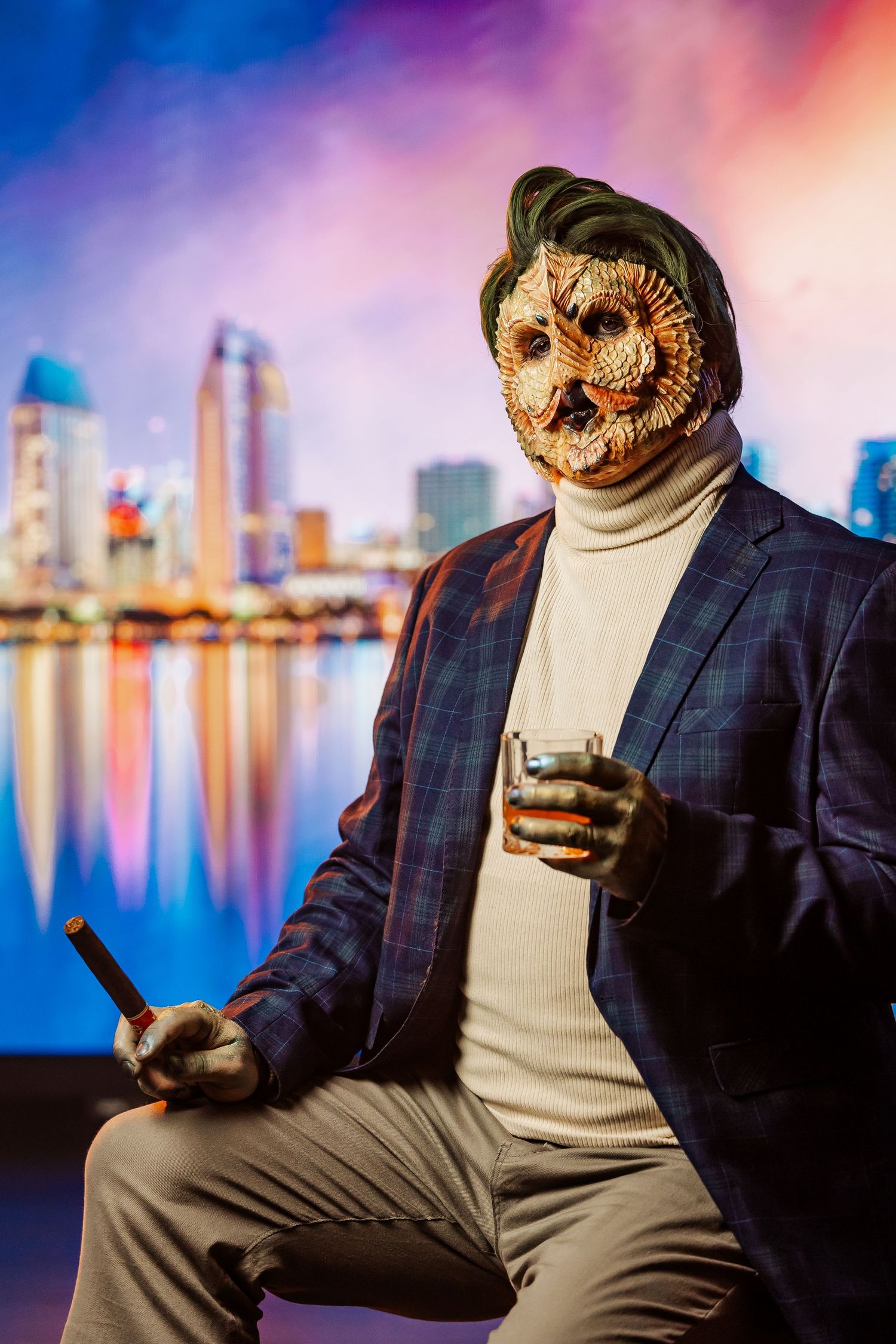 Person wearing realistic owl mask in business suit holding cigar and whiskey glass against city backdrop.