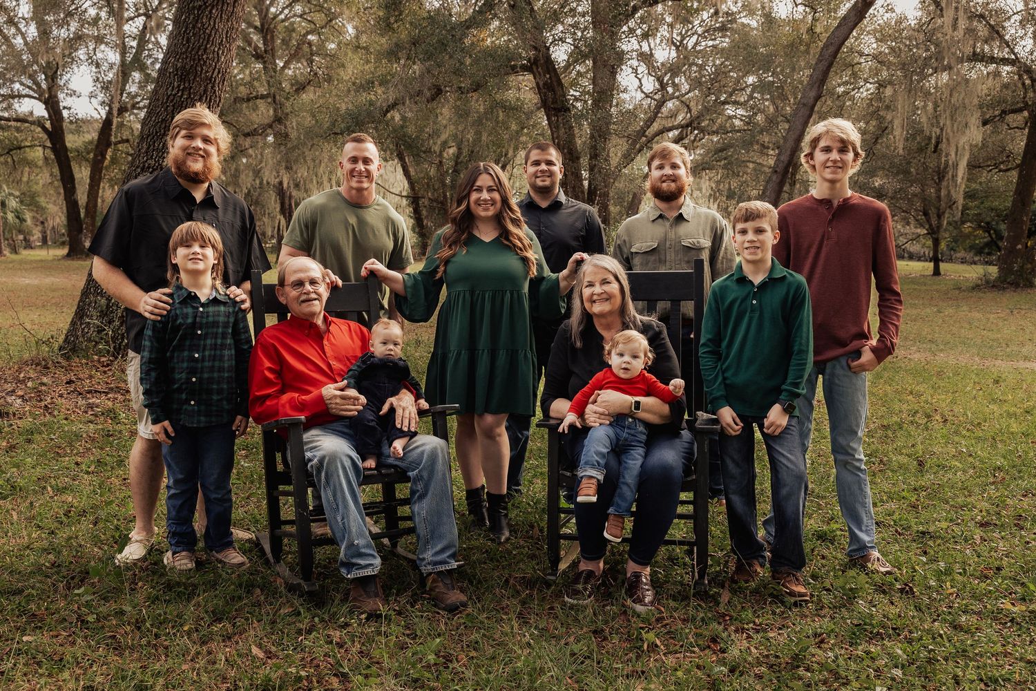 Extended family portrait with grandparents seated in rocking chairs and adult children standing outdoors.