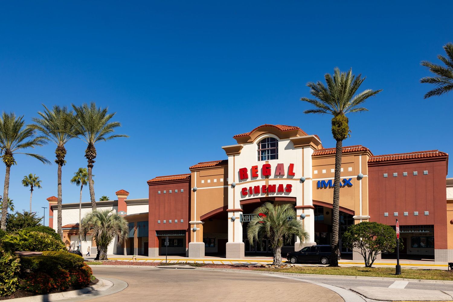 Regal Cinemas IMAX theater exterior with palm trees under a clear blue sky in a sunny location.