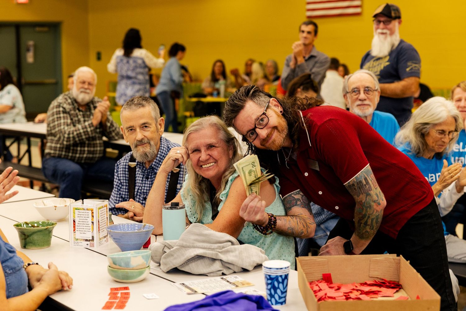 Happy group of people smiling and posing together at a community bingo fundraiser event indoors.