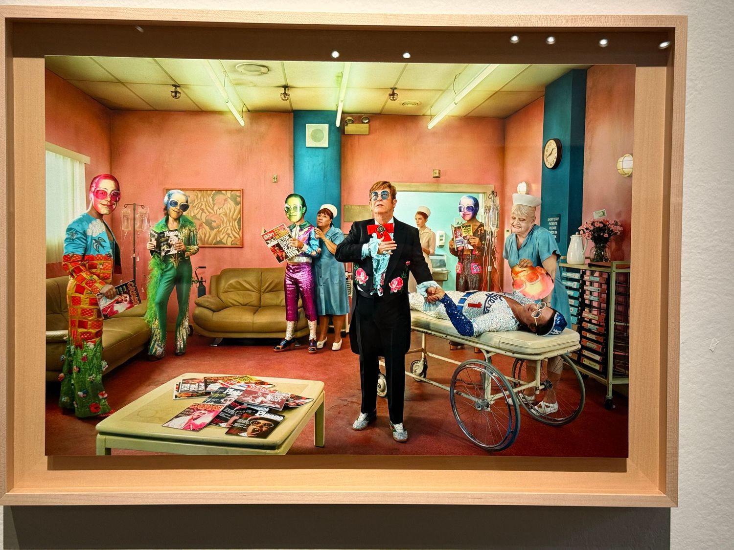 Colorful hospital corridor with pink walls and medical equipment displayed in illuminated alcoves along the hallway.