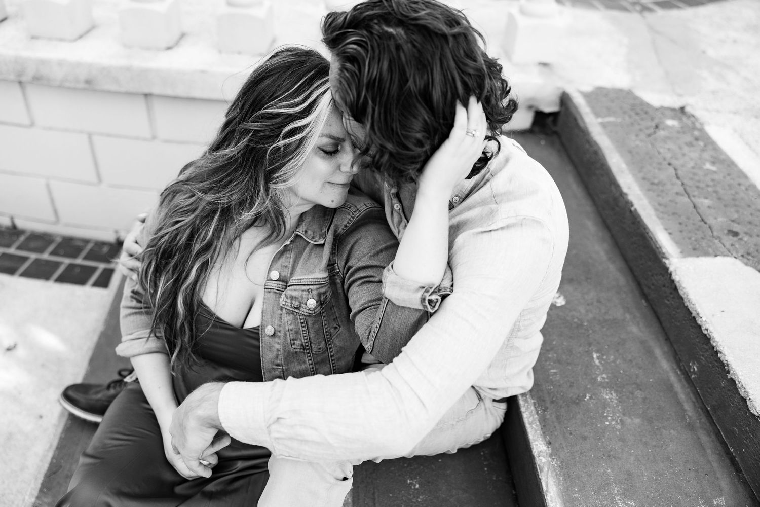 A couple shares an intimate embrace in a black and white outdoor engagement photo.
