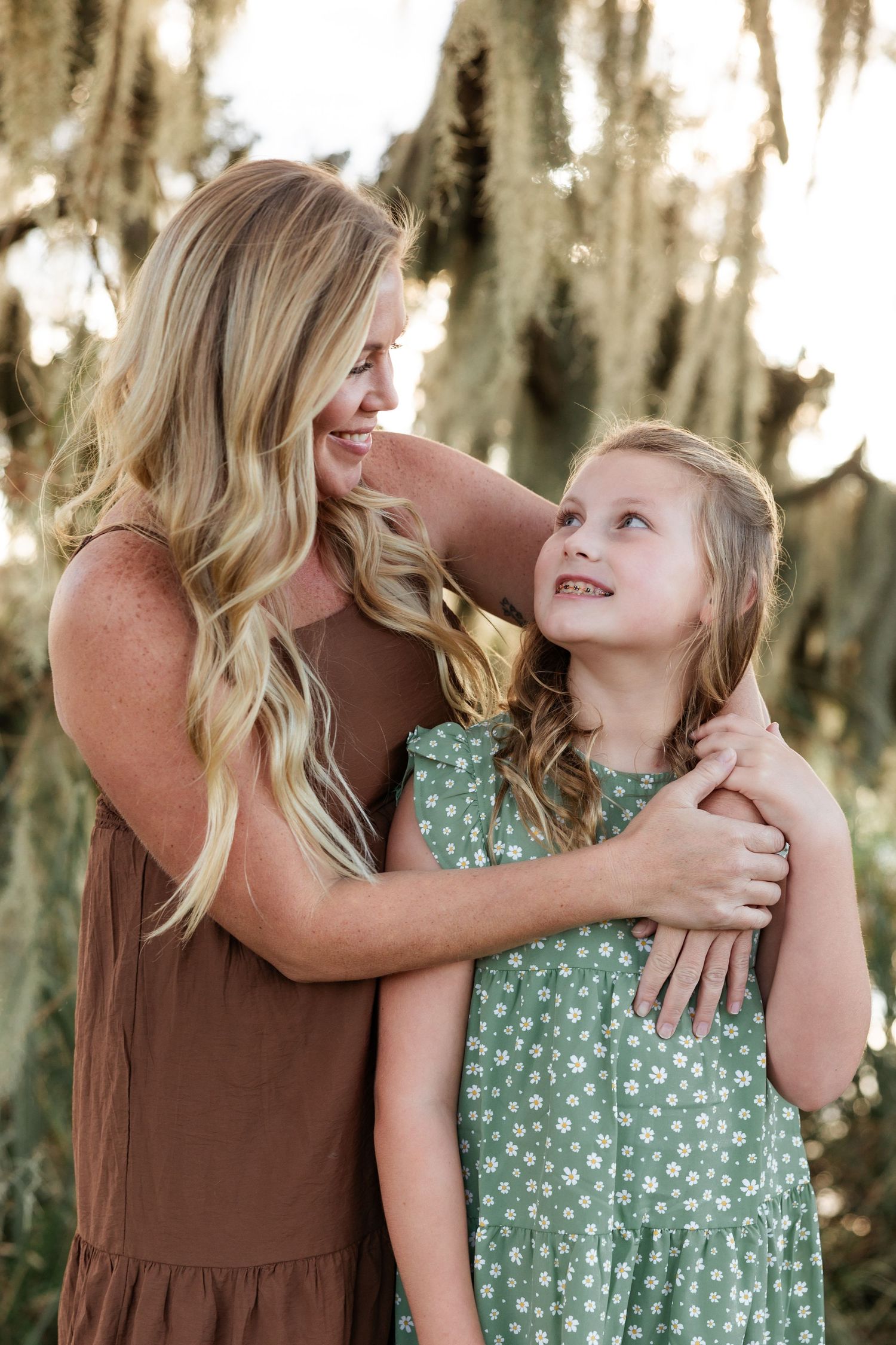 Candid moment between mother and daughter sharing a laugh under Spanish moss.