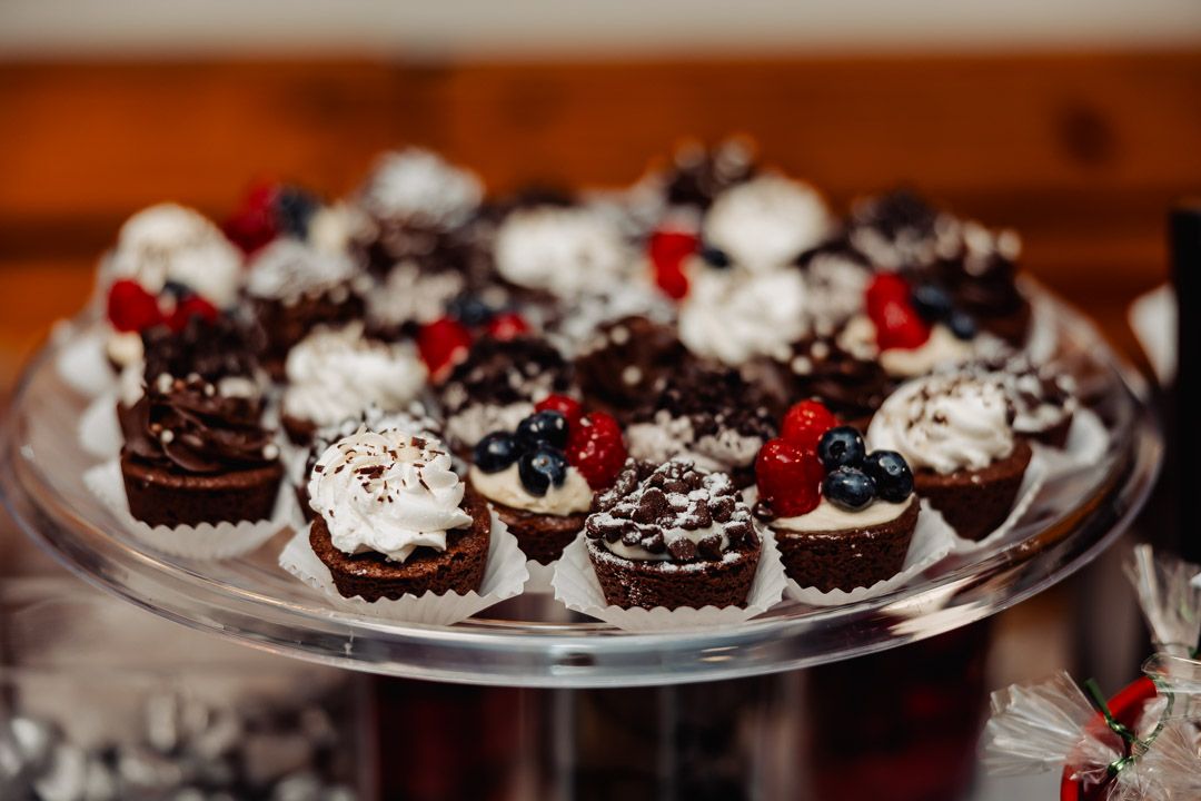 Chocolate desserts topped with whipped cream and fresh berries displayed on a glass platter.
