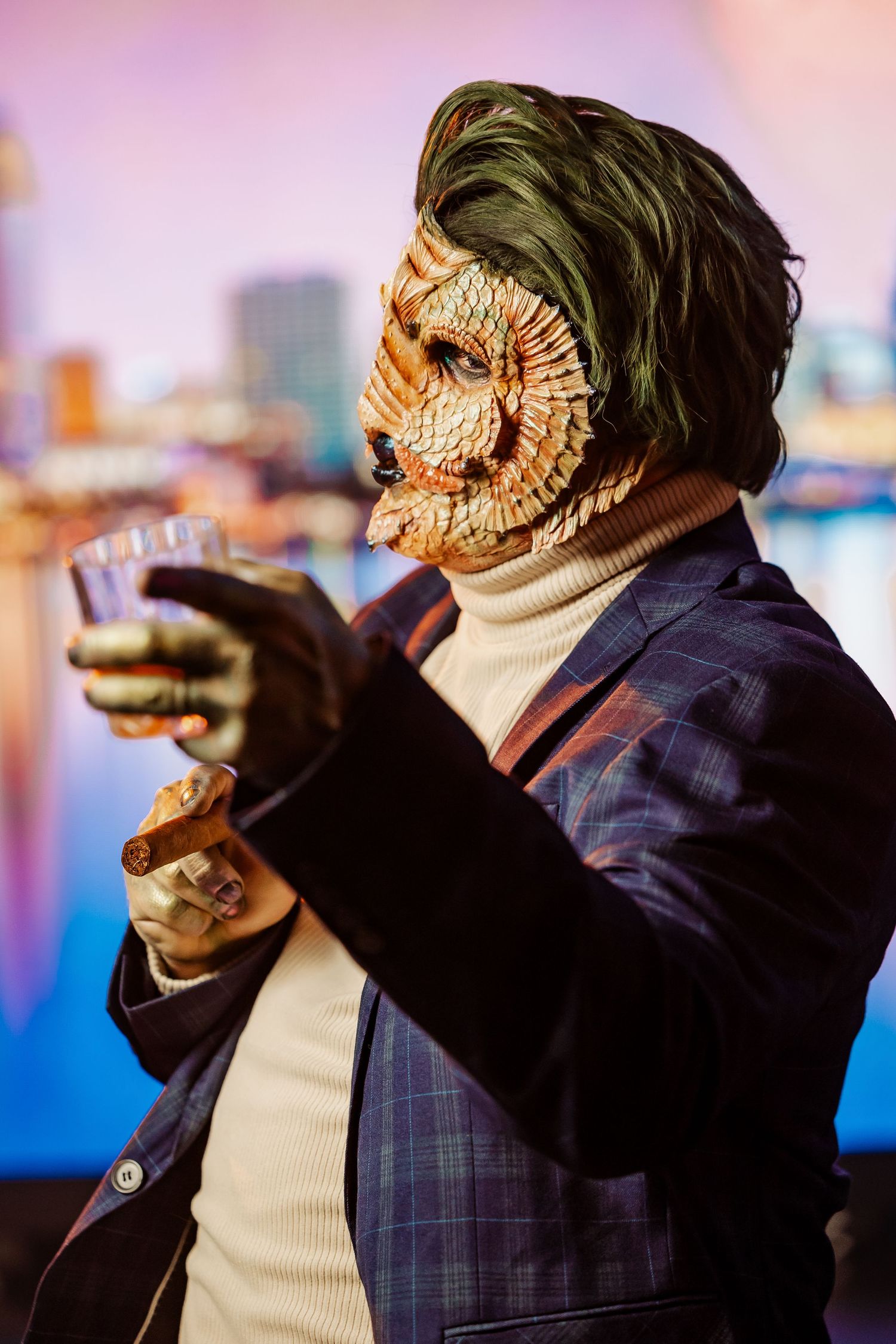 Person in plaid suit and theatrical mask poses against city skyline at dusk.