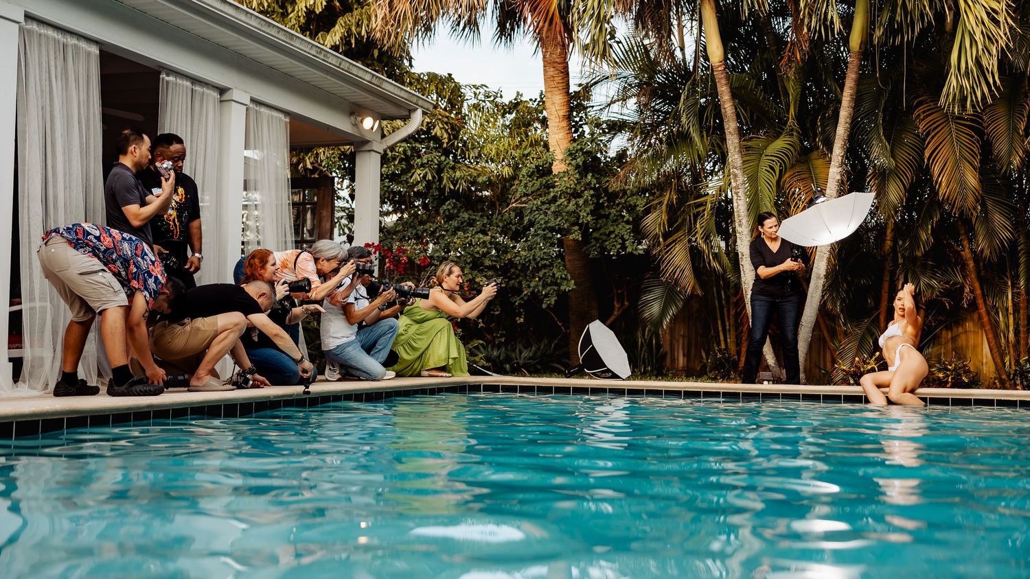 Multiple photographers capturing action shots around outdoor swimming pool.