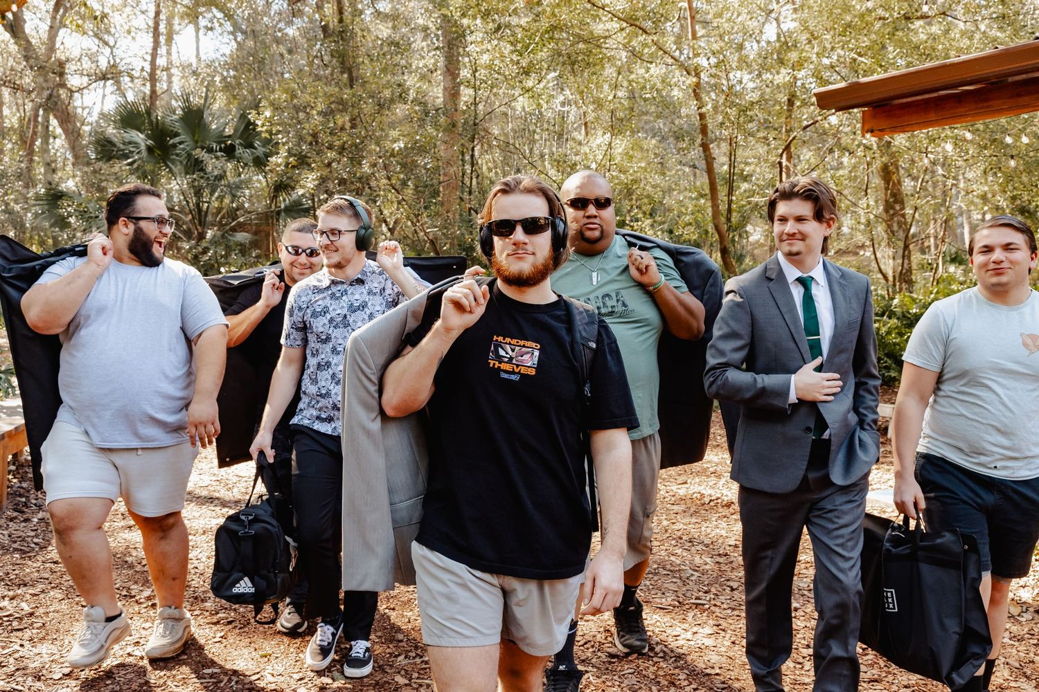 Group of wedding party members in casual attire gathered outdoors before ceremony.