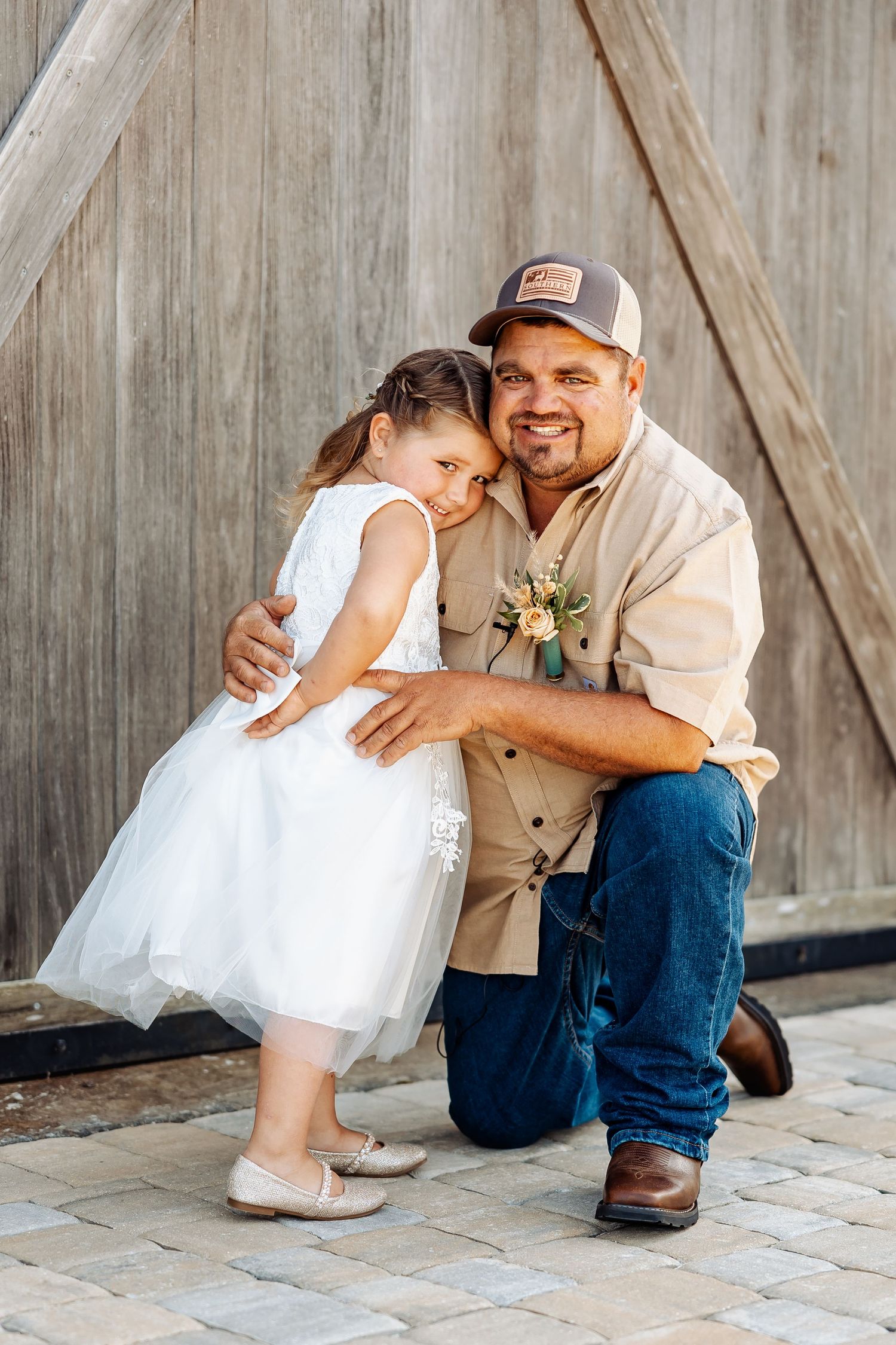 An emotional embrace shared between child and adult in front of a wooden barn backdrop.