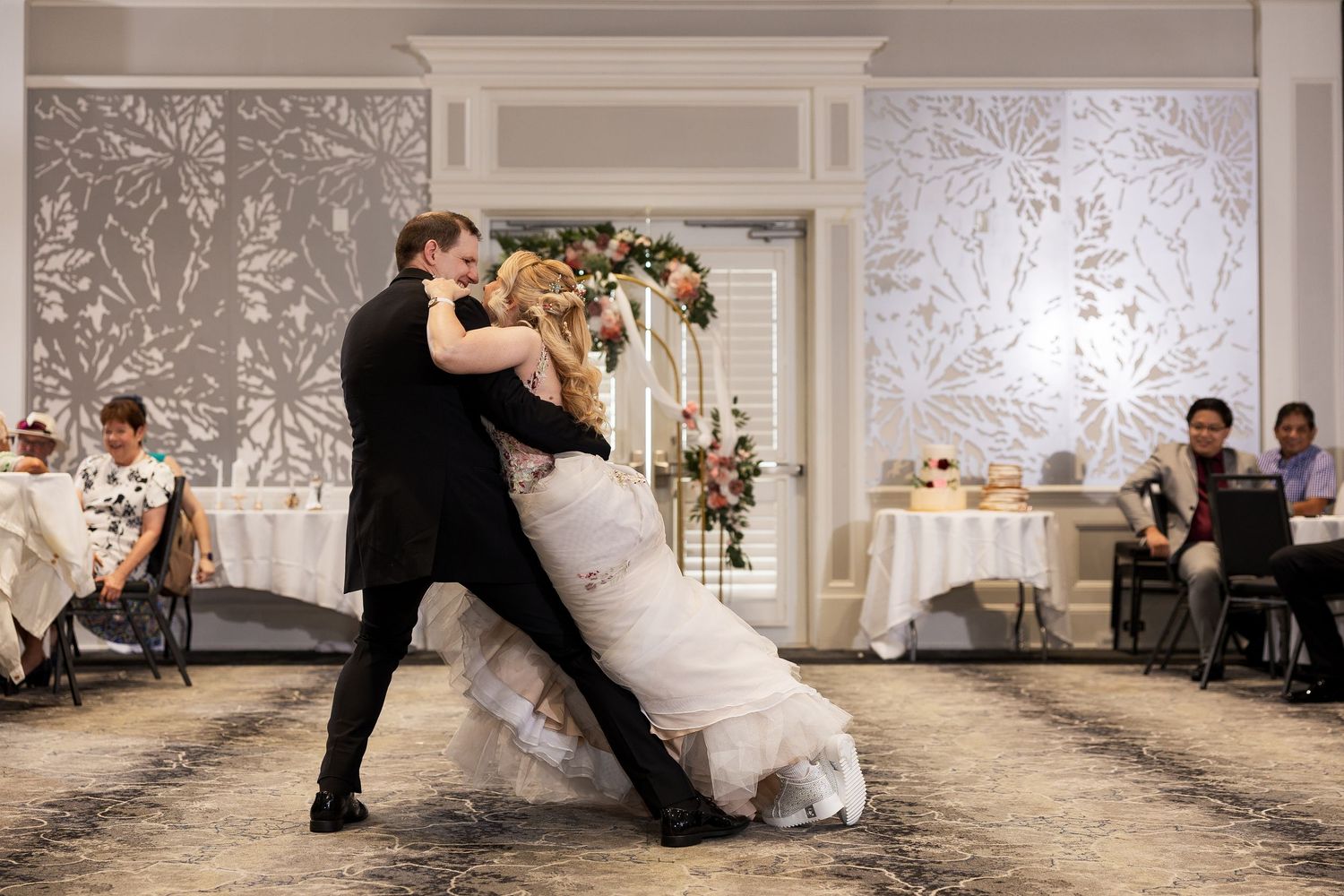 Groom dips bride dramatically on the dance floor during their first dance at the wedding reception.