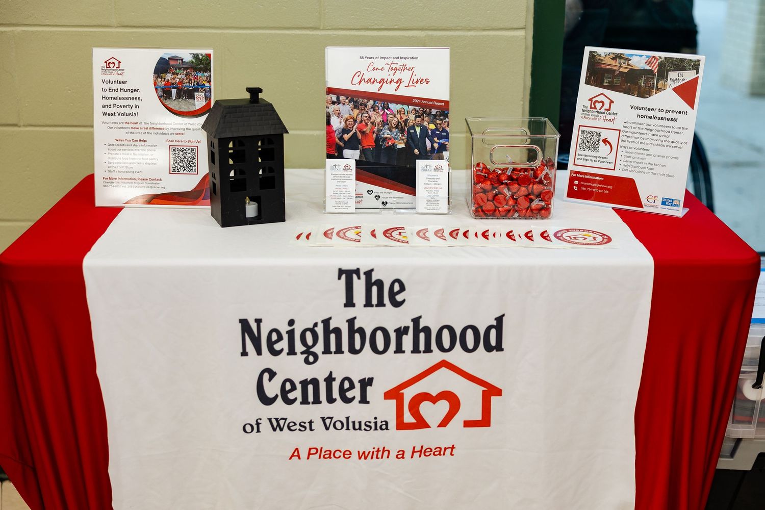The Neighborhood Center of West Volusia informational display table with red candy bowl and brochures.