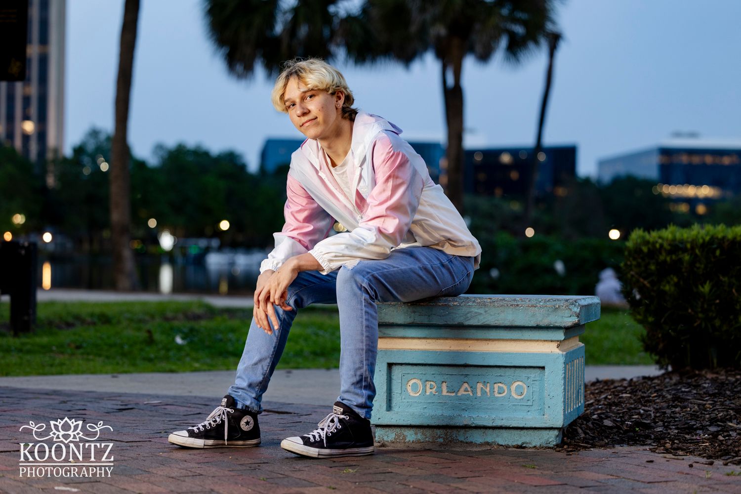 Evening portrait session on concrete bench with palm trees in background.