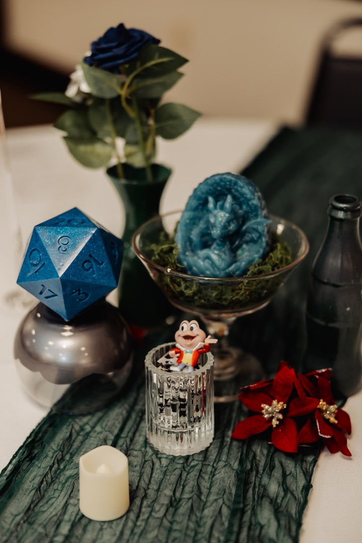 Tabletop display with blue D20 die, crystal, flowers, and decorative items.