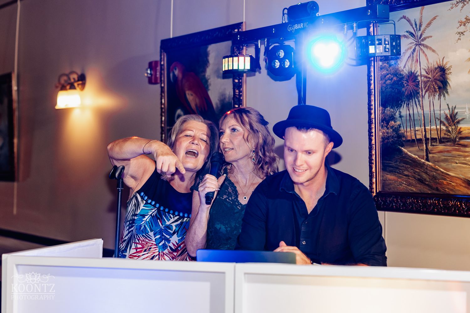 Entertainment crew performing with enthusiasm at wedding reception with blue stage lighting.