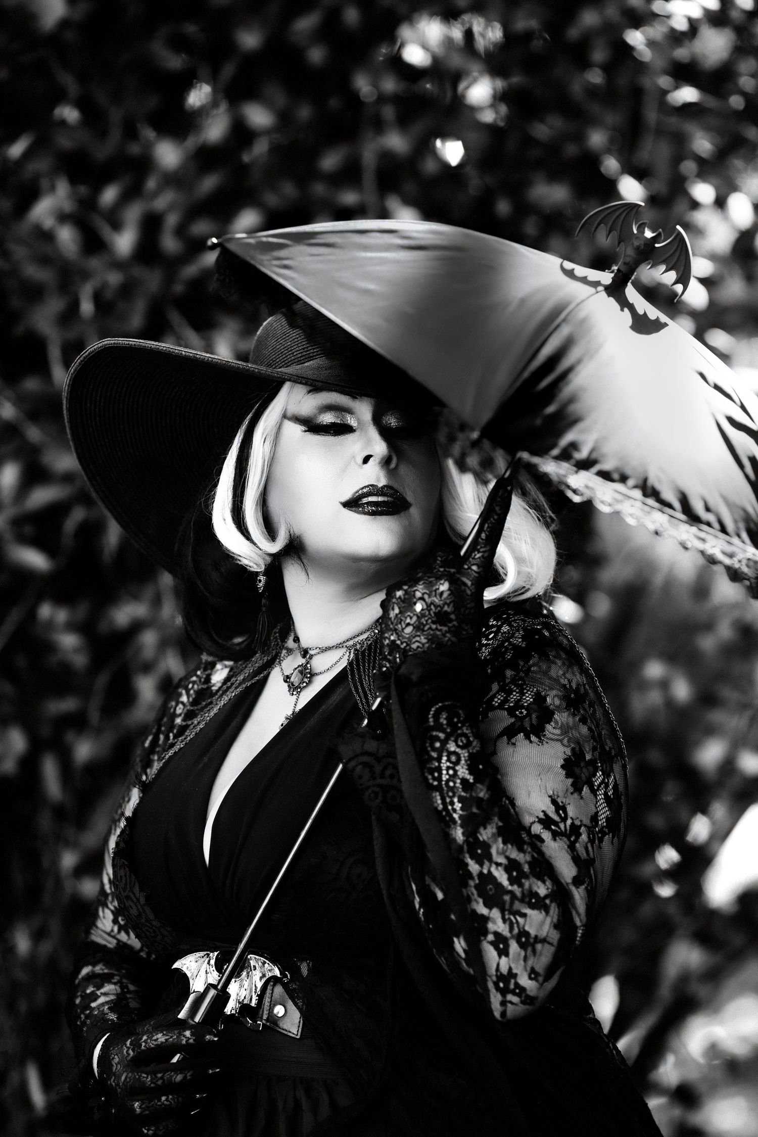 Black and white portrait of a woman in pirate hat and lace outfit holding a sword outdoors.