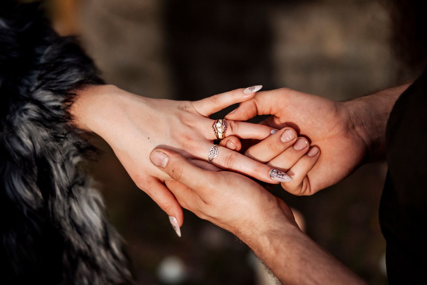 Close-up of bride and groom exchanging rings with ornate wedding bands during Viking-themed ceremony.