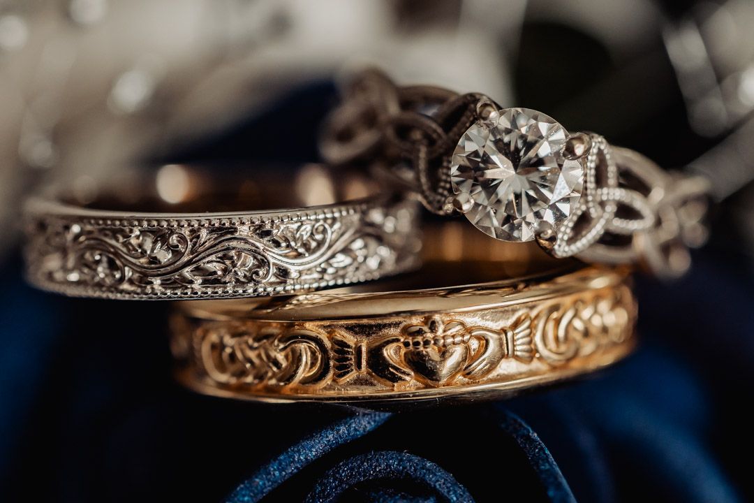 Macro shot of three ornate wedding rings with detailed metalwork and diamonds.