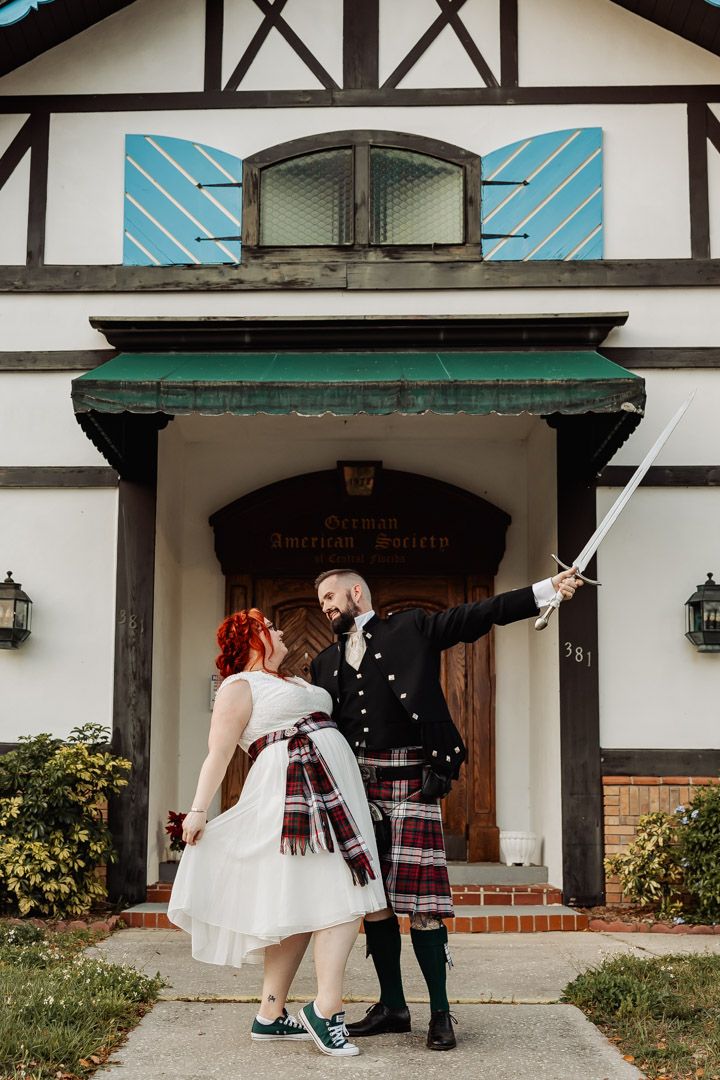 Groom in Scottish kilt raising sword outside German American Society building.