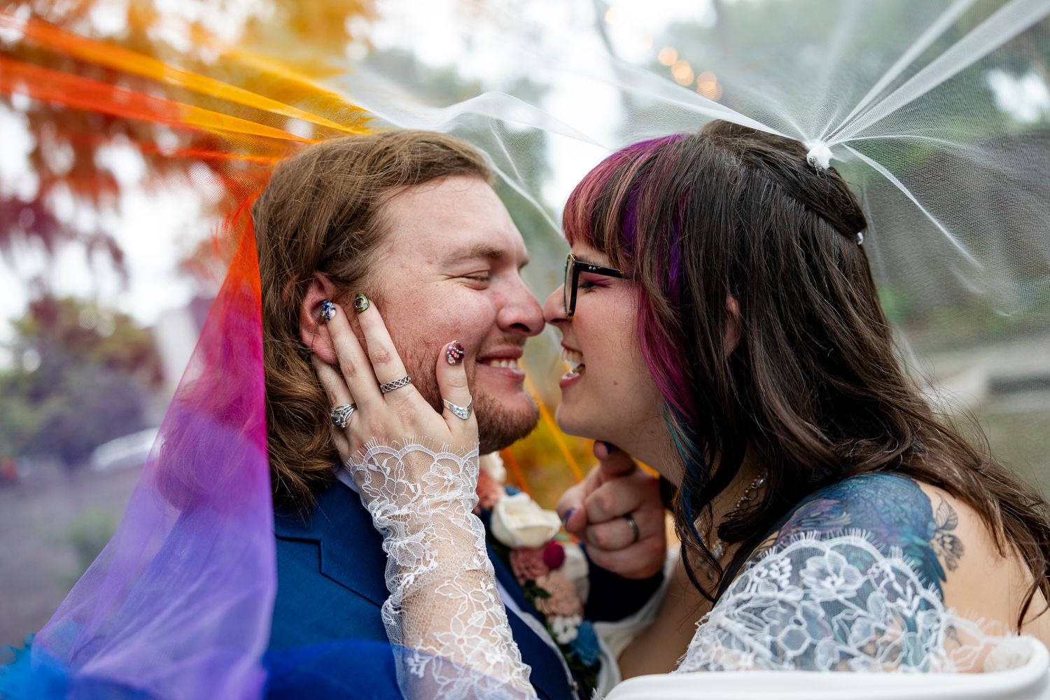 A bride and groom share a romantic kiss under a clear umbrella on their rainy wedding day.