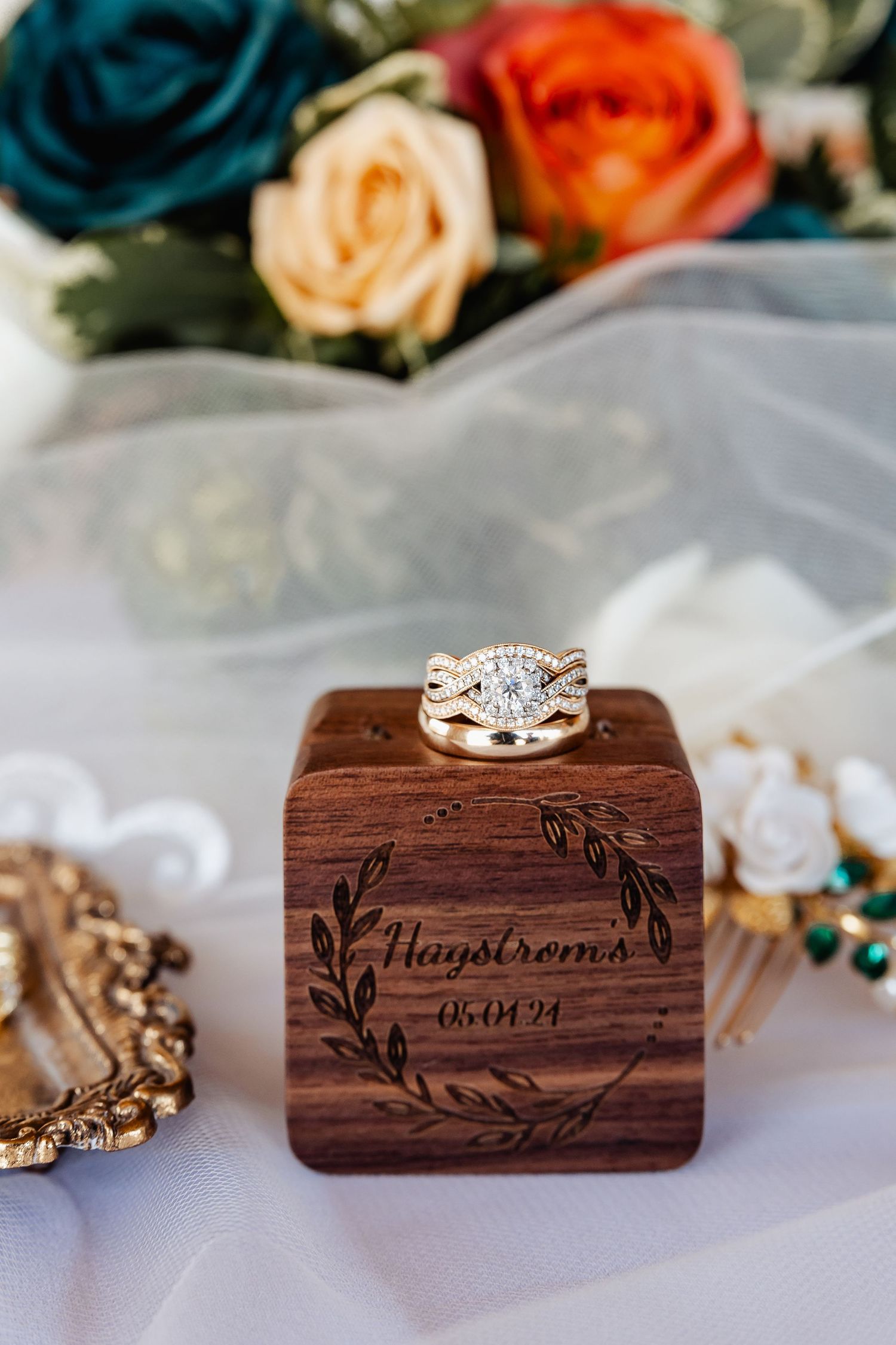 Diamond engagement ring on custom wooden box with engraved wedding date and florals.