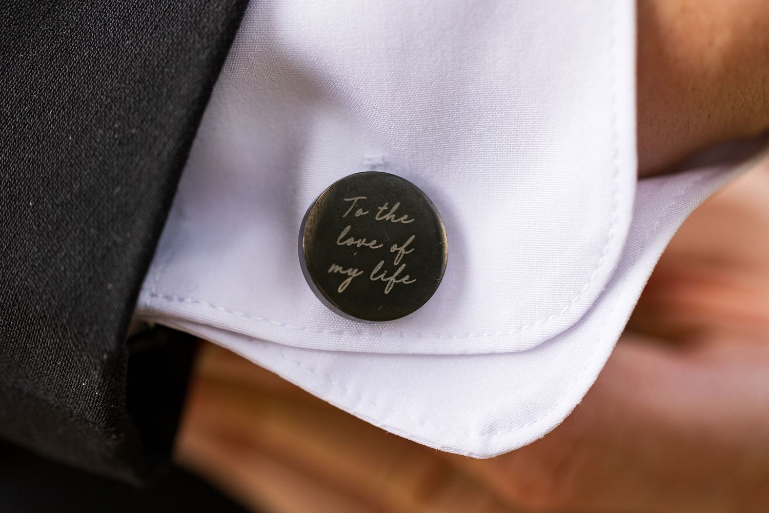 Elegant gold cufflink engraved with 'To the love of my life' on a groom's white dress shirt.