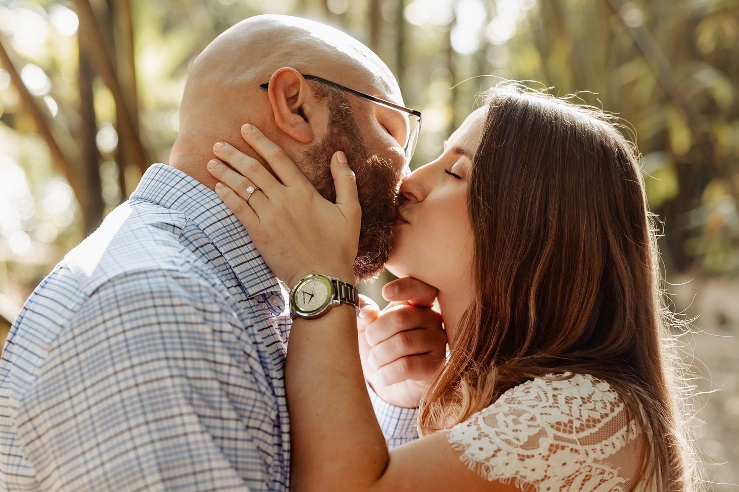 Close-up of a couple sharing a romantic kiss outdoors in warm, golden sunlight.