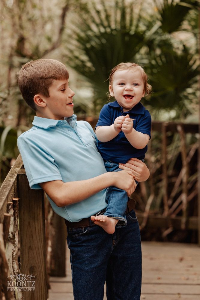Two people sharing a joyful moment outdoors in casual attire against a palm tree background.