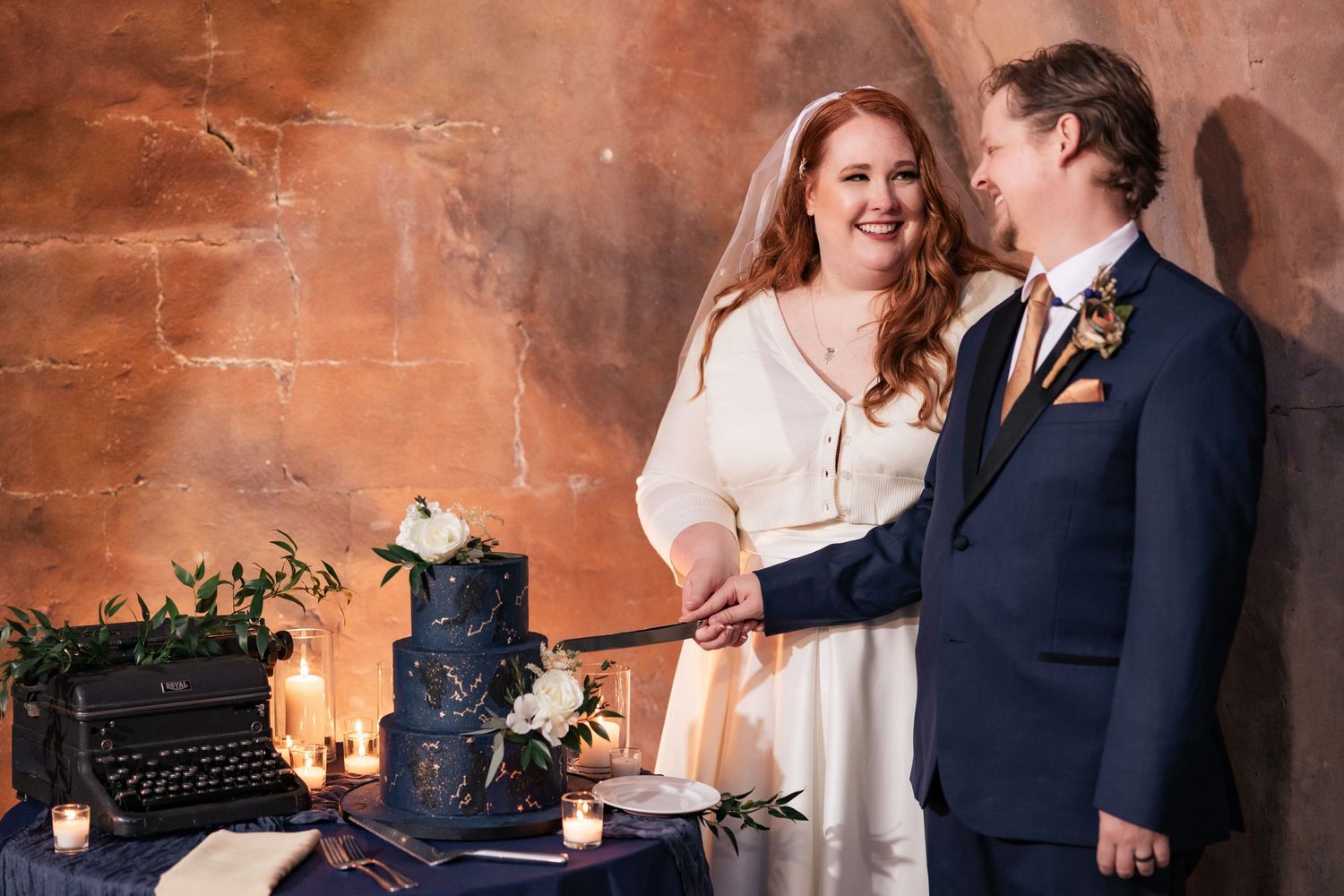 Bride and groom cutting navy blue celestial wedding cake together.