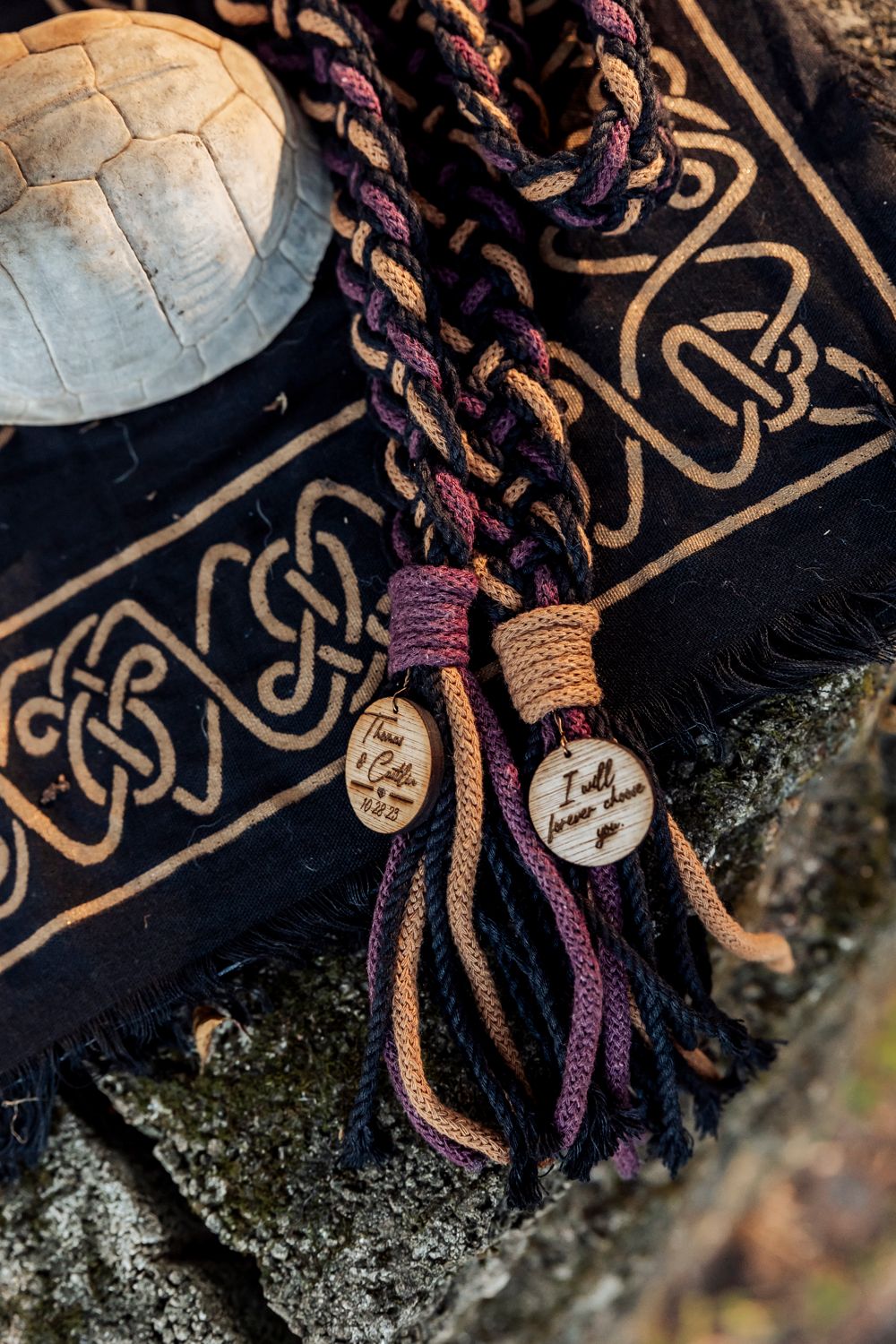 Decorative braided cords with wooden pendants on Celtic patterned fabric.