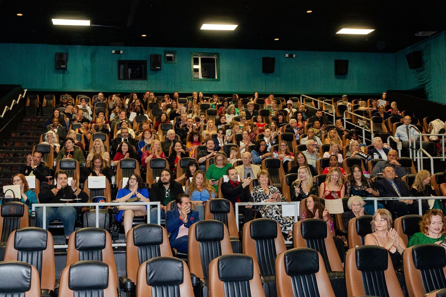 A large audience fills a cinema theater during a movie premiere screening event.