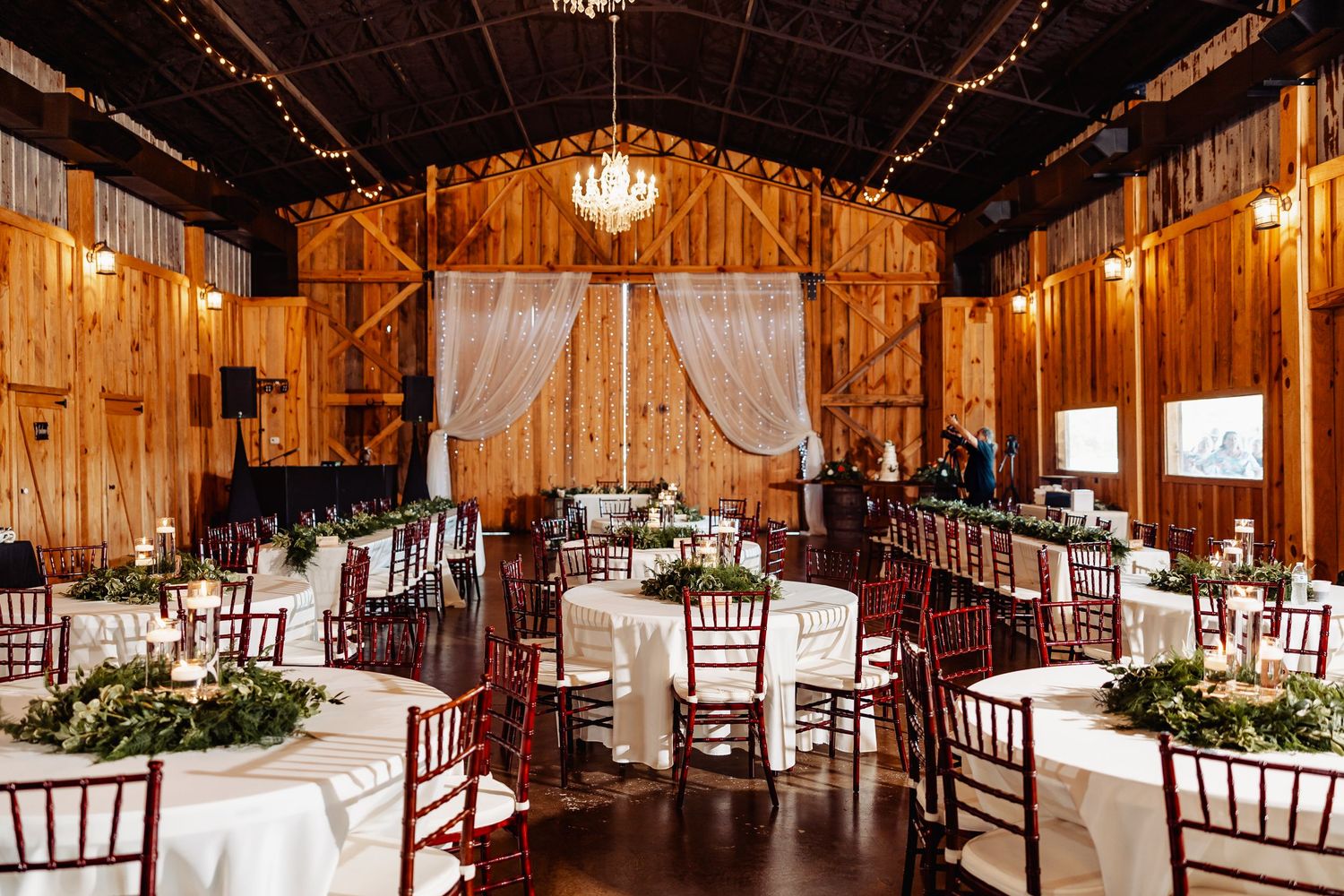 Rustic wooden barn wedding venue with elegant table settings and chandeliers.
