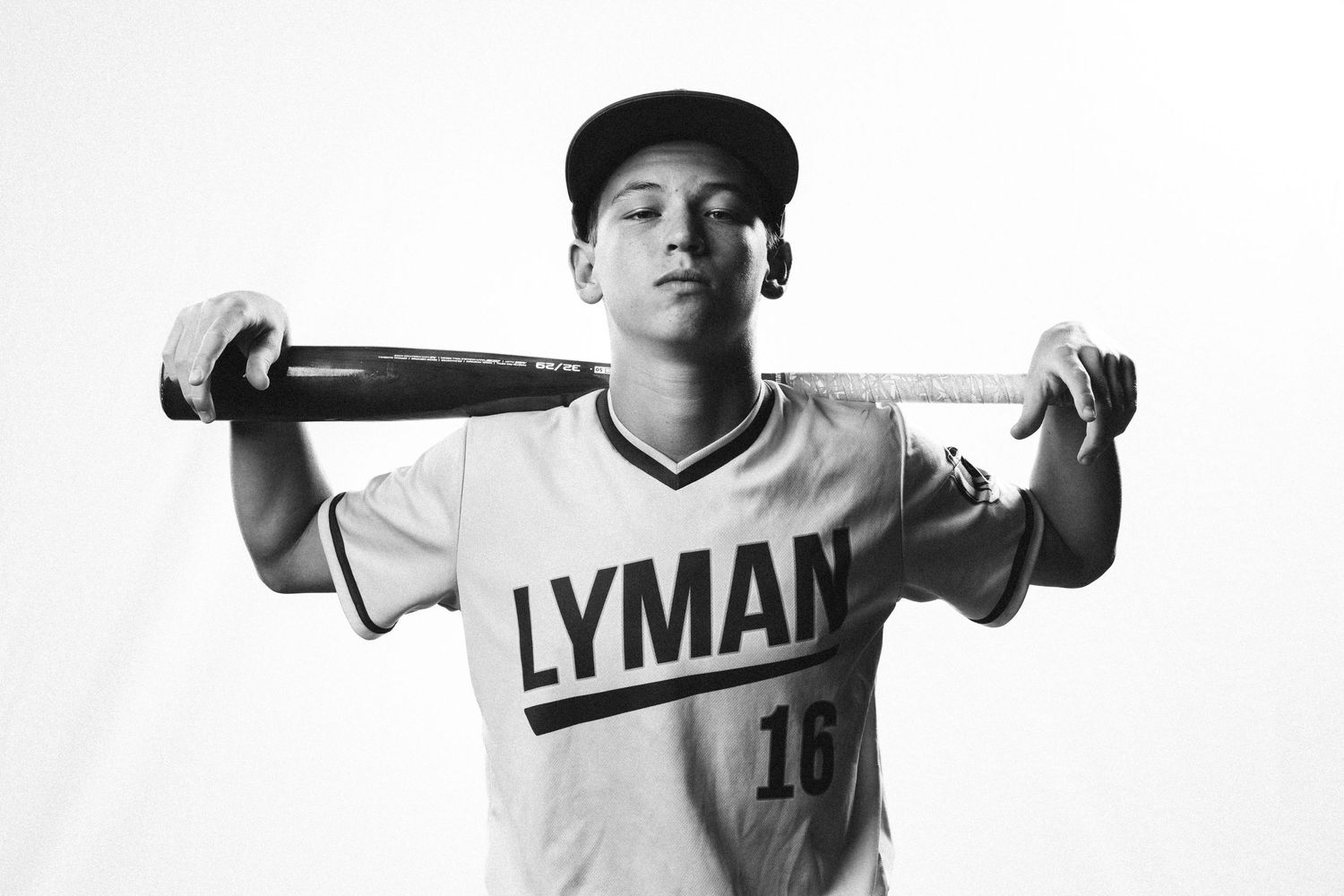Baseball player in Lyman jersey poses with bat across shoulders in black and white portrait.