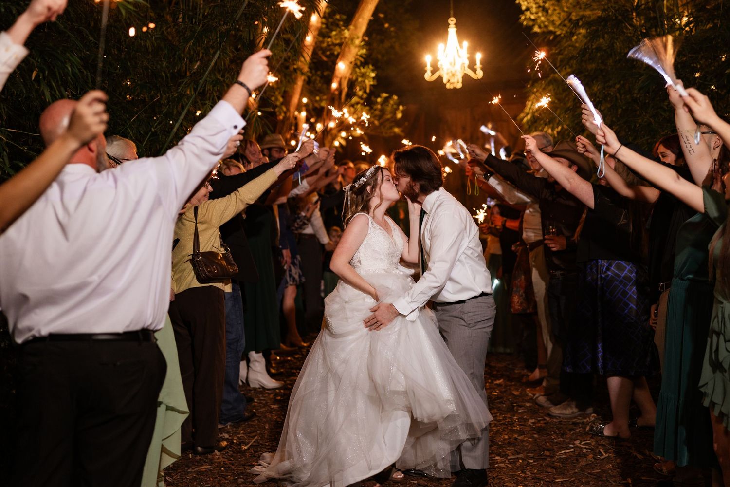 Nighttime sparkler exit with couple sharing romantic moment surrounded by wedding guests.