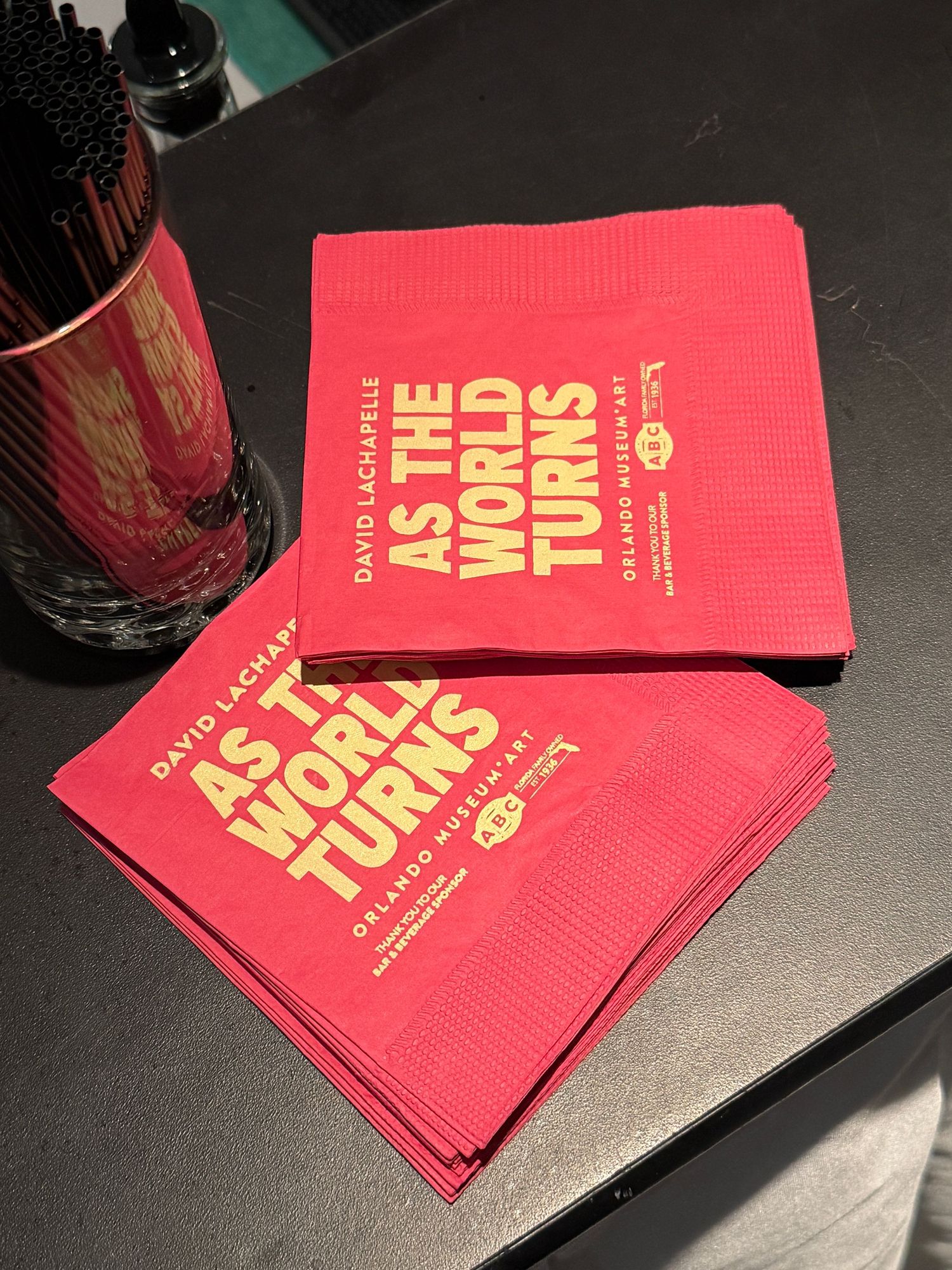 A series of red promotional cards or tickets arranged in a sequence on a dark surface with gold text visible.