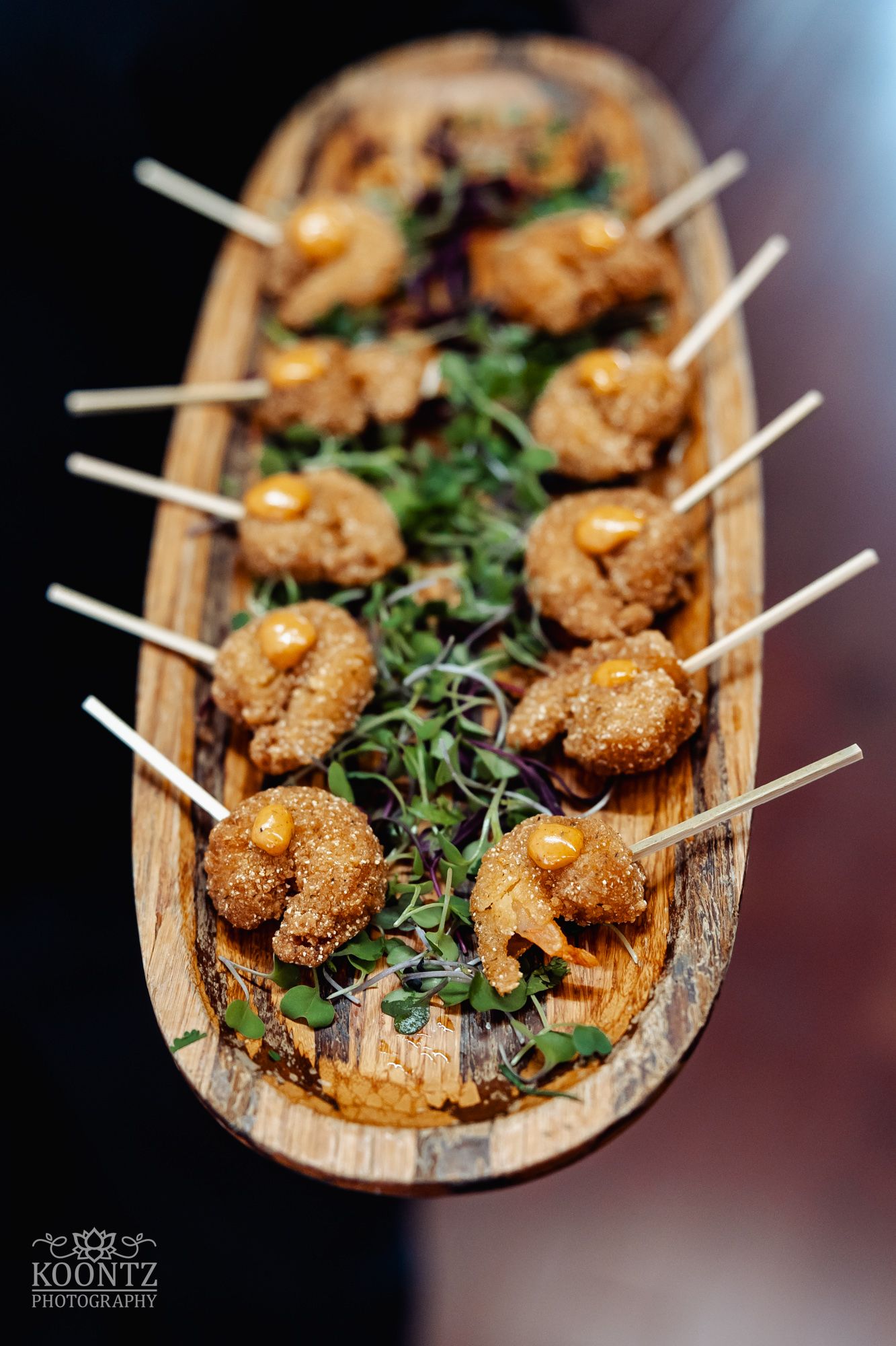 Glazed shrimp appetizers on wooden skewers garnished with fresh herbs.