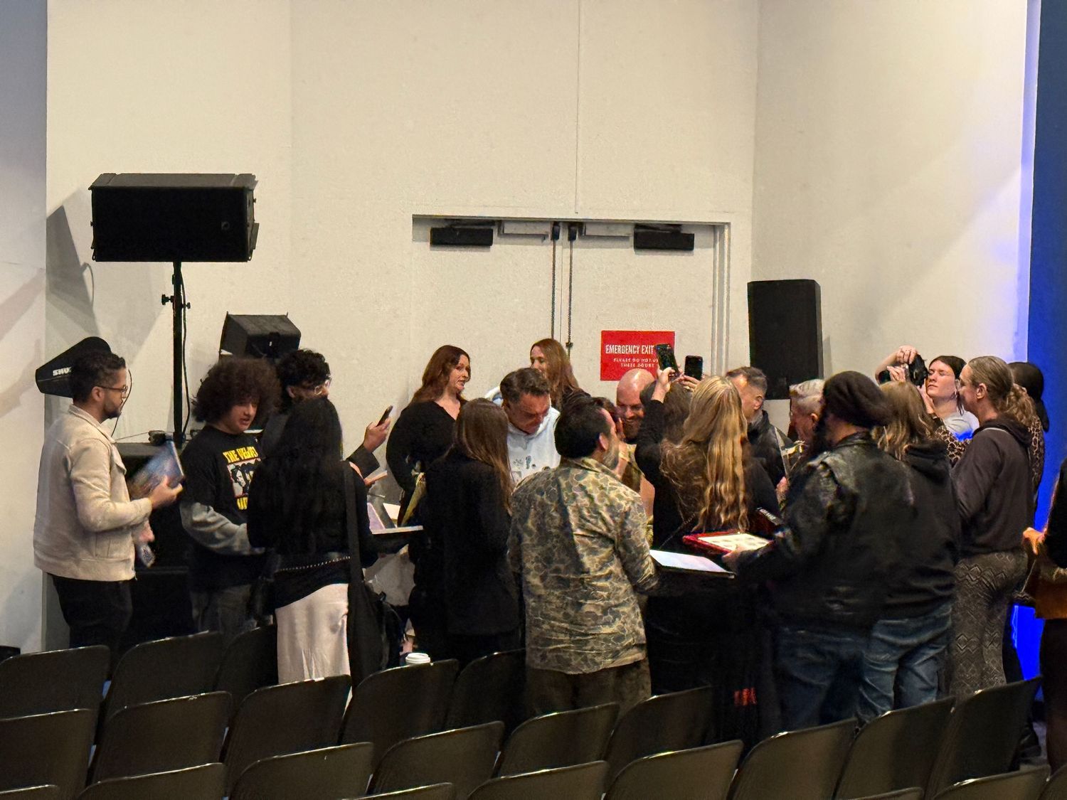 A group of people gathered around tables in a conference room setting with audio equipment and chairs.
