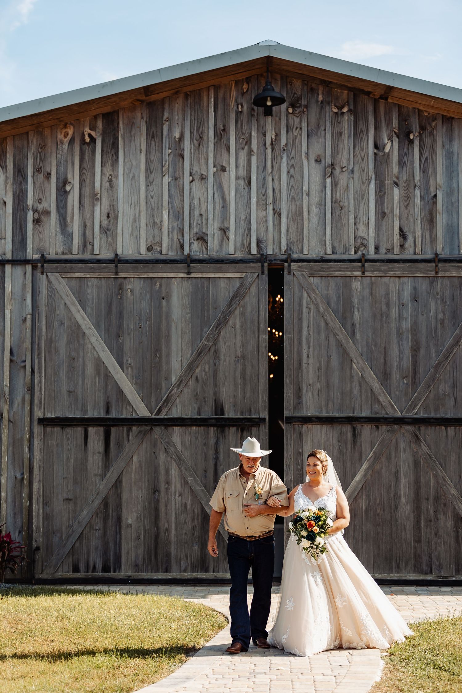 Wedding couple poses in front of rustic wooden barn doors.