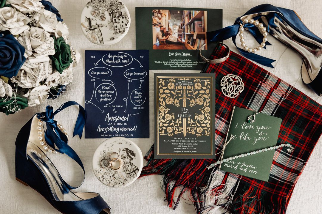 Wedding stationery flat lay featuring navy and plaid accents with floral decorations.