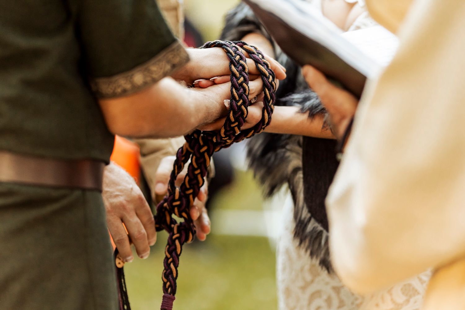 Close-up of handfasting ceremony with braided cord binding couple hands in Viking wedding ritual.