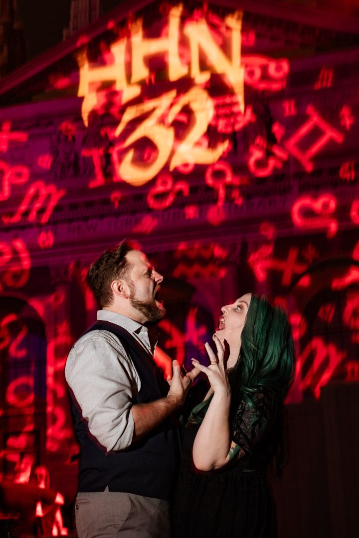 Couple playfully screaming at each other beneath the dramatic red HHN 32 Halloween Horror Nights sign.