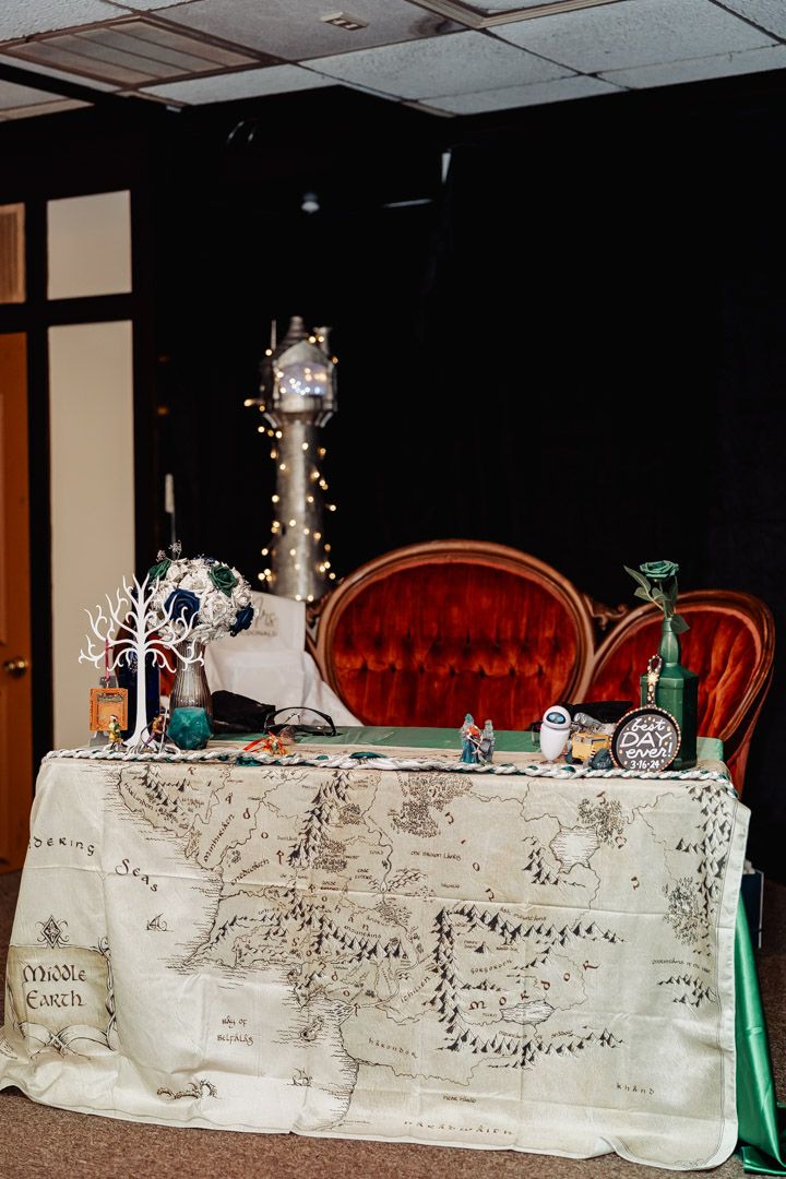 A fantasy-themed display table with a map tablecloth, decorated with fairy lights and vintage props.