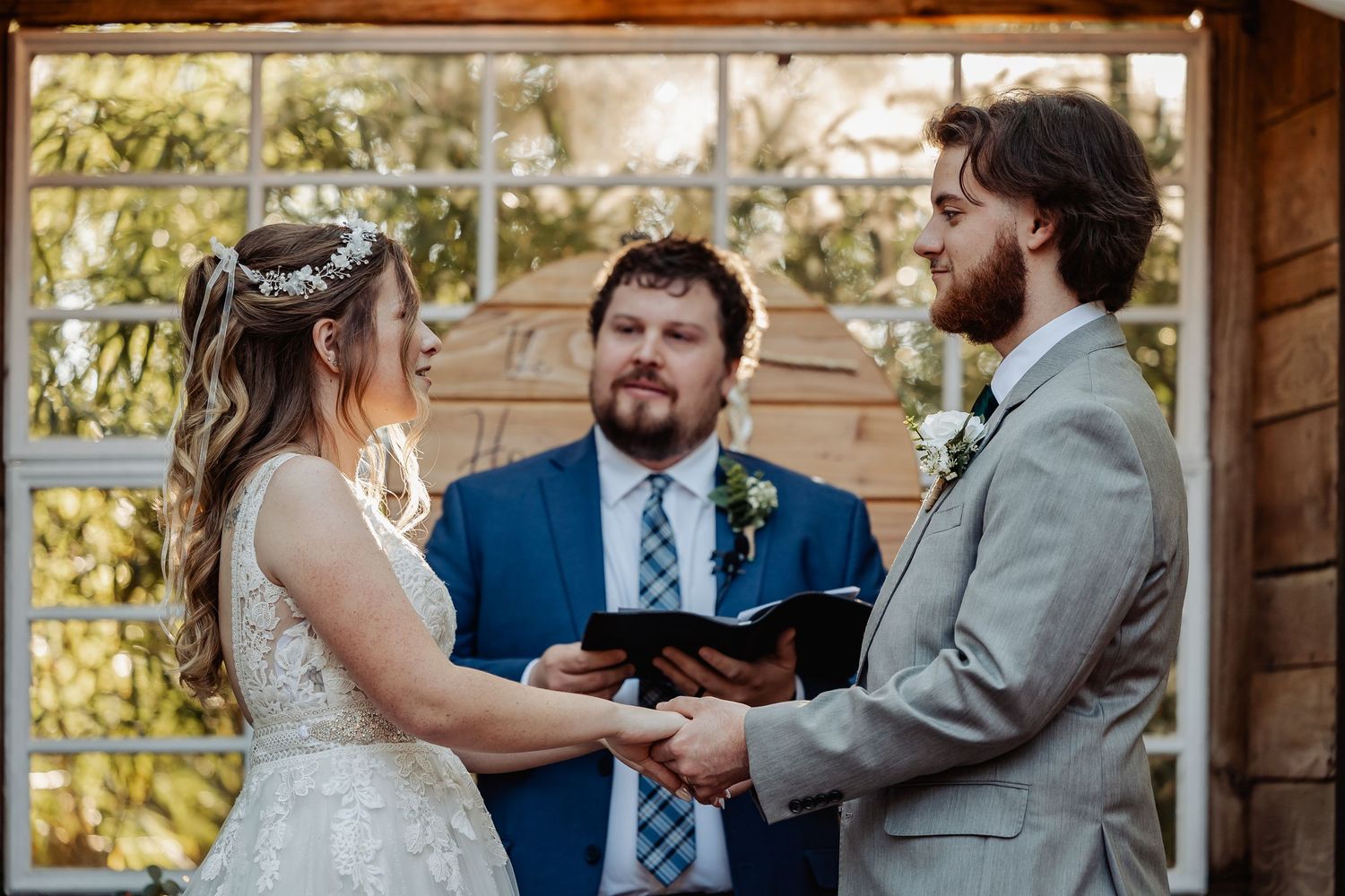 Intimate wedding ceremony moment at rustic wooden altar with exchange of vows.
