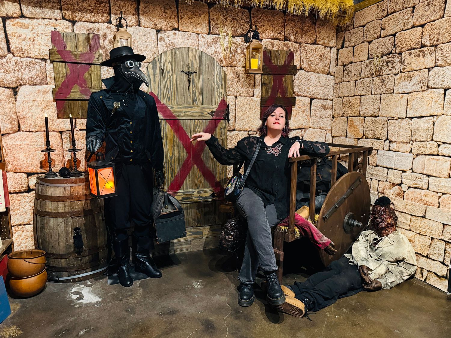 Plague doctor costume display in a medieval dungeon-themed room with stone walls, barrels, and dramatic Halloween decor.