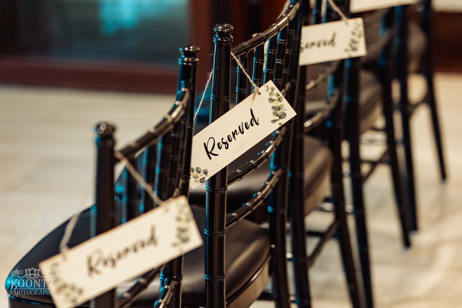 Wedding reception chairs marked with reserved signs on elegant black railings.