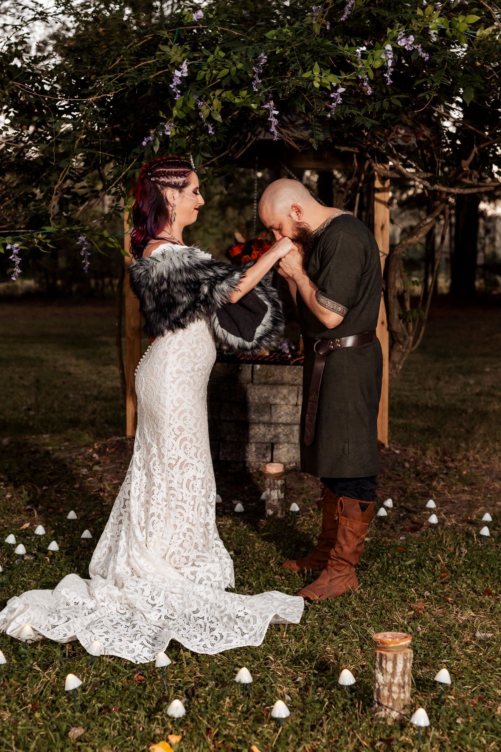 A medieval-inspired wedding ceremony outdoors with candlelit decorations and fantasy elements.