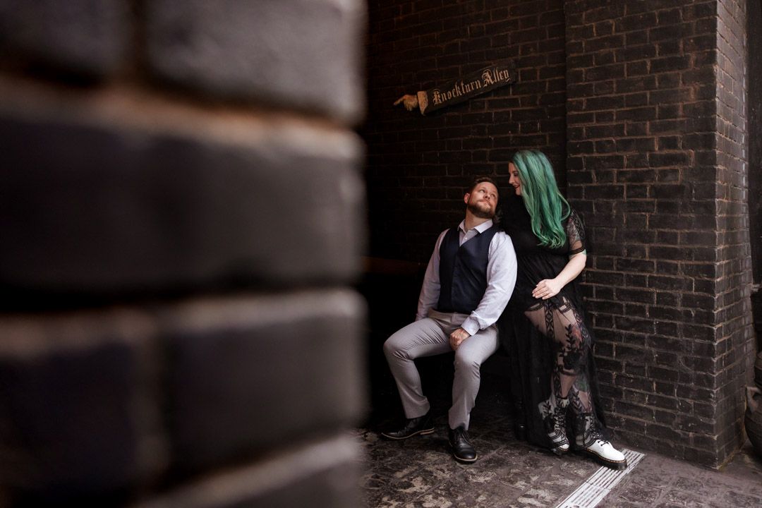 Couple relaxing in a narrow brick alley corner near a Knockturn Alley sign at Universal Studios.